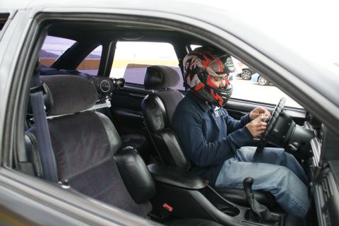 1993 Ford Taurus - Driver in a racing helmet operates the steering wheel inside a 1993 Ford Taurus.