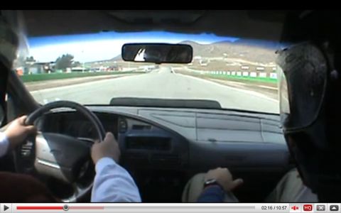 1993 Ford Taurus - View from inside a car as it drives on a race track, with two occupants wearing helmets.