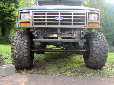 1986 Ford Bronco - Lifted Ford truck front end with large off-road tires and a chrome grille.