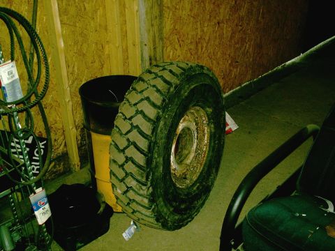 2001 Dodge 2500 - A single tire and rim is shown leaning against a wall in what appears to be a garage or storage area.