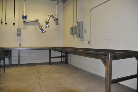 1996 Ford Bronco - A workshop scene with metal workbenches and overhead fume extraction arms.