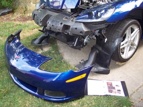 2006 Chevrolet Corvette - A blue Corvette's front bumper is detached, revealing the car's internal components and front end structure.
