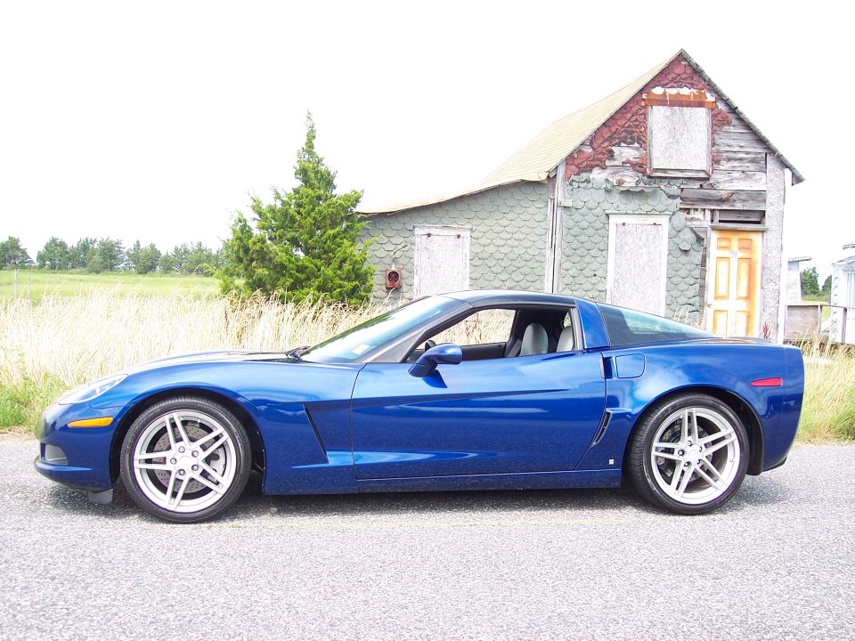 Blue sports car parked in front of an old, weathered house