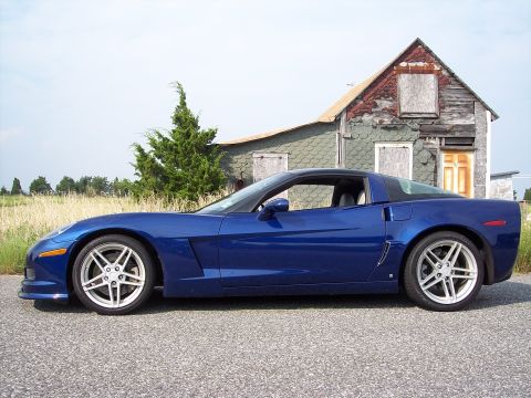 2006 Chevrolet Corvette - Side profile of a blue 2006 Chevrolet Corvette parked on a road near an old, weathered house.