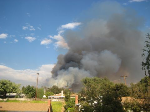 1996 Ford Bronco - A large plume of dark smoke rises into the sky, obscuring the horizon over a neighborhood.