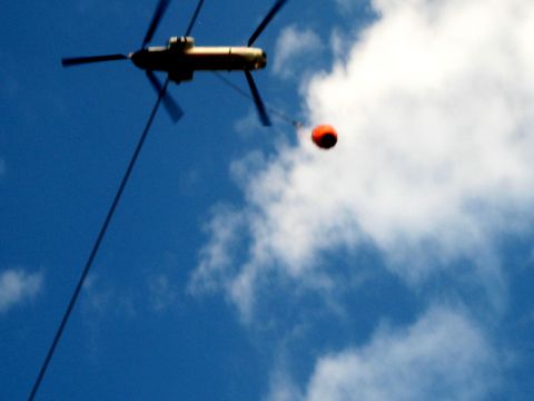 1996 Ford Bronco - Helicopter with a water bucket is seen against a cloudy blue sky.
