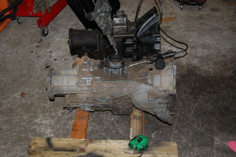 1994 Ford Bronco - Transmission and transfer case assembly resting on wooden blocks in a garage.