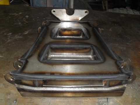 1996 Ford Bronco - A fabricated metal component with prominent welds sits on a workbench.