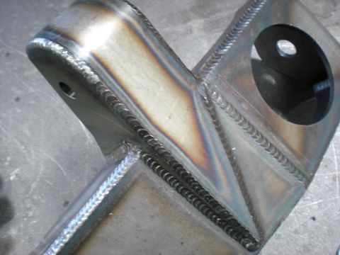 1996 Ford Bronco - Close-up of a metal bracket showing numerous welds and two holes, one with a black washer.