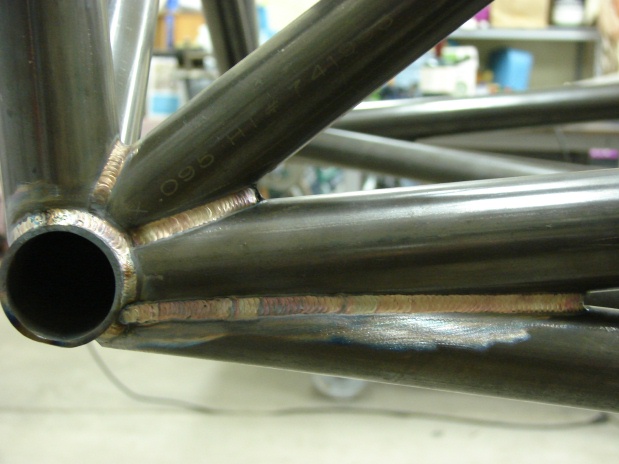 Close-up of welded metal tubing, possibly part of a chassis or roll cage. Text "x.095 H" is visible