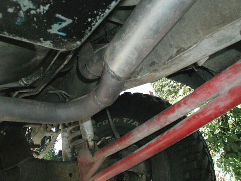 1985 Ford Bronco - Underside view of vehicle exhaust system and suspension components, with a tire visible.