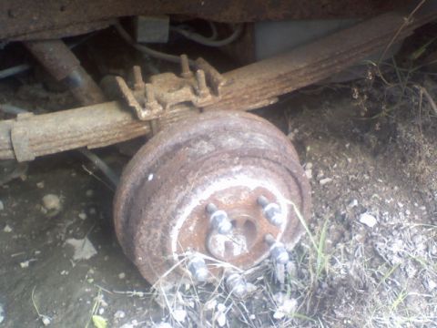 1992 Ford Bronco - Close-up of a heavily rusted rear axle drum brake assembly, showing leaf springs and suspension components.