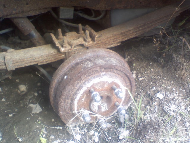 Rusty rear axle drum brake assembly with leaf springs attached