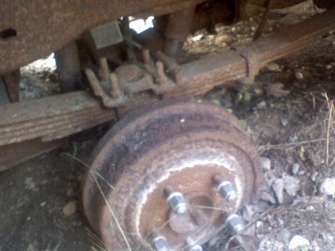 1992 Ford Bronco - Close-up view of a rusty rear axle drum brake assembly and leaf springs.