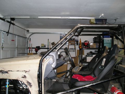 1986 Toyota Hilux - Custom interior of a pickup truck features racing seats, a roll cage, and a modified dashboard, seen in a garage setting.