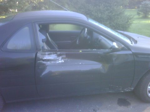 1996 Ford Bronco - The driver's side door and window of a dark coupe are heavily damaged.