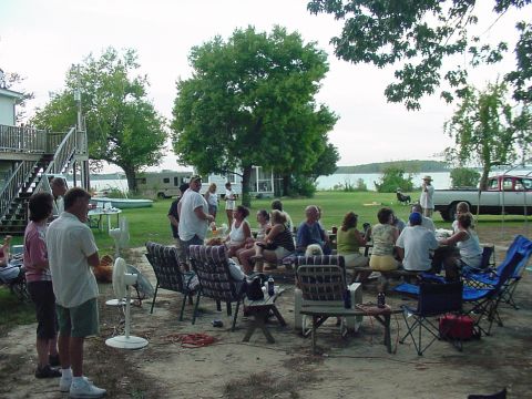 1978 Ford F-250 - A group of people enjoy an outdoor gathering near a lake, with a white pickup truck visible in the background.