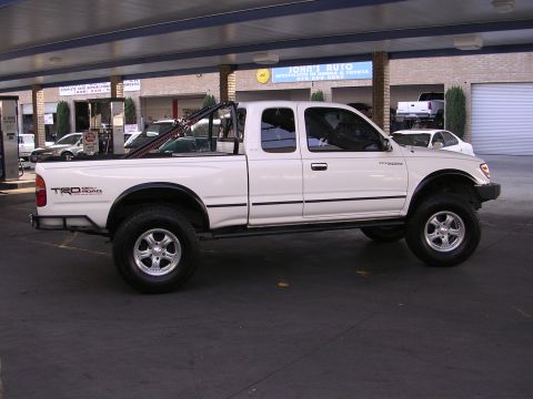1999 Toyota Tacoma - This white 1999 Toyota Tacoma TRD pickup truck is shown from the side, a lifted suspension and off-road tires.