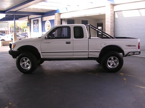 1999 Toyota Tacoma - This lifted Toyota Tacoma pickup truck is shown from the side, aftermarket wheels and a roll bar in the bed.