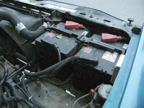 1985 Ford Bronco - Engine bay view showing dual battery setup with red terminal covers.
