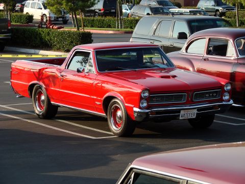 1972 Ford Ranchero - This red 1965 Pontiac GTO coupe utility is parked in a lot with other vehicles.