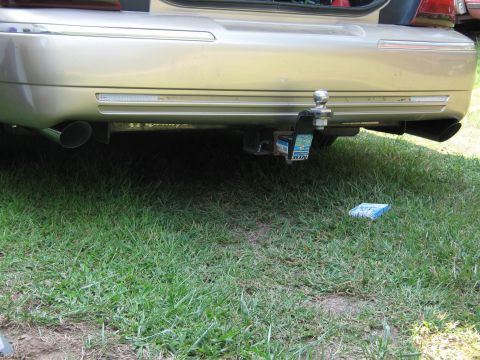 2000 Mercury Grand Marquis - Rear view of a gold 2000 Mercury Grand Marquis, showing the trailer hitch and dual exhaust pipes.