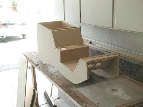 1985 Ford Bronco - This unfinished wooden center console features dual cup holders and storage compartments, likely for a custom vehicle interior.