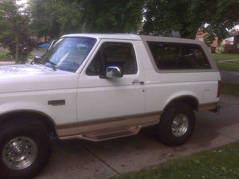 1995 Ford Bronco - Side profile of a white 1995 Ford Bronco, tan lower body trim and running boards.
