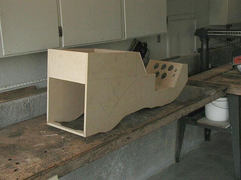 Raw MDF center console fabrication with round gauge cutouts on a garage workbench