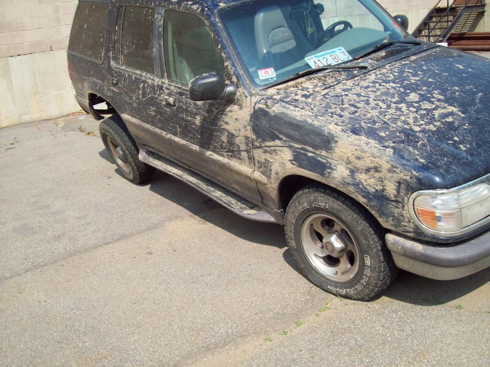 1997 Mercury Mountaineer covered in mud, front passenger side view