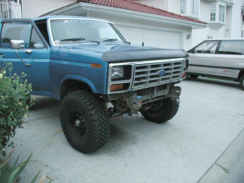 Blue lifted Ford Bronco with front bumper removed, big off-road tires, in a driveway
