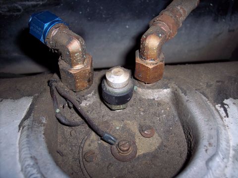 1981 Kenworth W900A - Detail of a fuel sending unit with associated plumbing and wiring, showing wear and dirt accumulation.