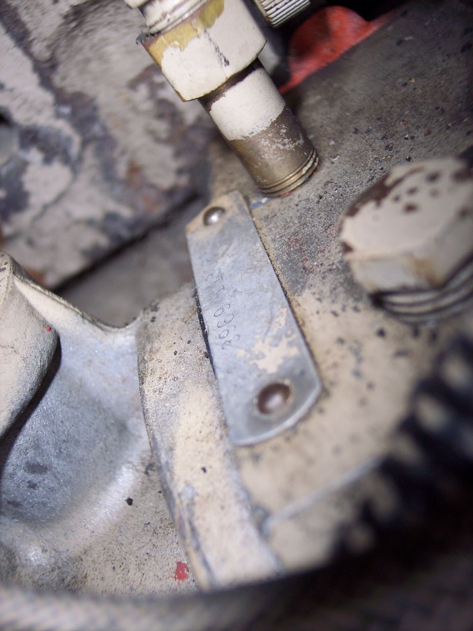 Close-up of a metal plate stamped with numbers, attached to an engine component