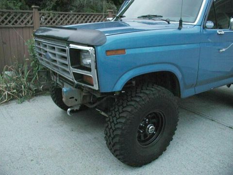 1985 Ford Bronco - Front view of a blue Ford Bronco with a chrome grille and large tires.