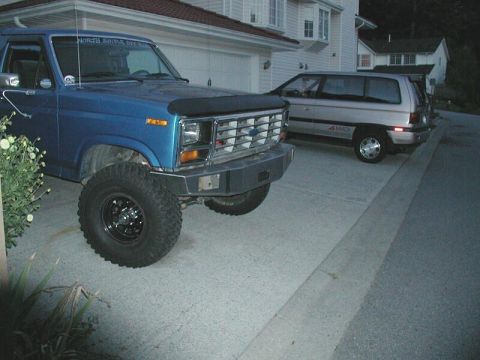 1985 Ford Bronco - Blue Ford Bronco with aftermarket bumper and large tires parked in a driveway.