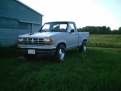 2001 Dodge 2500 - A gray Ford Ranger pickup truck is parked on grass next to a metal building with a field in the background.