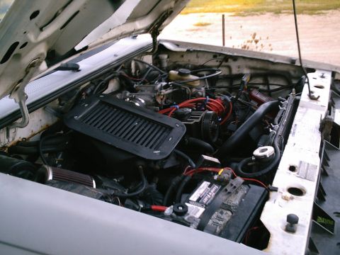 2001 Dodge 2500 - The engine bay of a white Ford Ranger shows an aftermarket air intake and red spark plug wires.