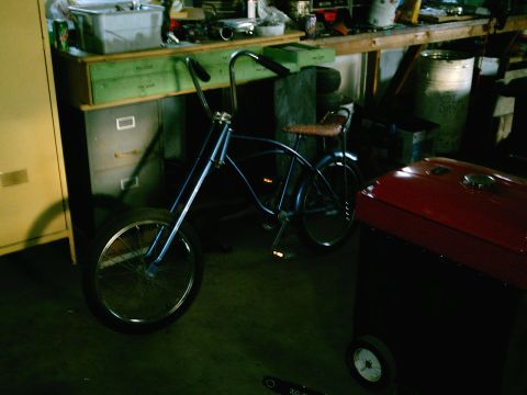 2001 Dodge 2500 - A blue cruiser bicycle is parked in a workshop next to a red tool chest and a workbench.