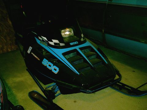 2001 Dodge 2500 - A black and blue snowmobile is parked next to a teal vehicle.