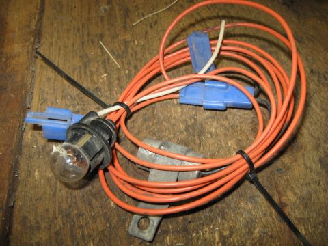 1979 Chevrolet Camaro - Wiring harness with a light bulb socket and blue connectors, laid out on a wooden surface.