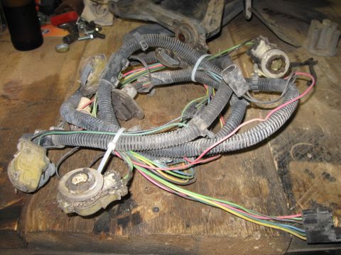 1979 Chevrolet Camaro - A tangled engine wiring harness lies on a rough wooden workbench, showing various connectors and wires.