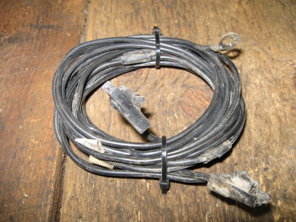 Tangled black wiring harness with plastic connectors on a wooden surface