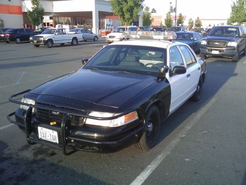 1900 Bentley Turbo - A police car is parked in a lot with other vehicles visible in the background.