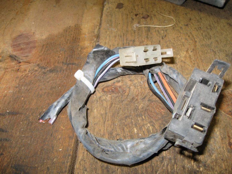 Wiring harness with two plastic connectors and multi-colored wires on a wooden surface