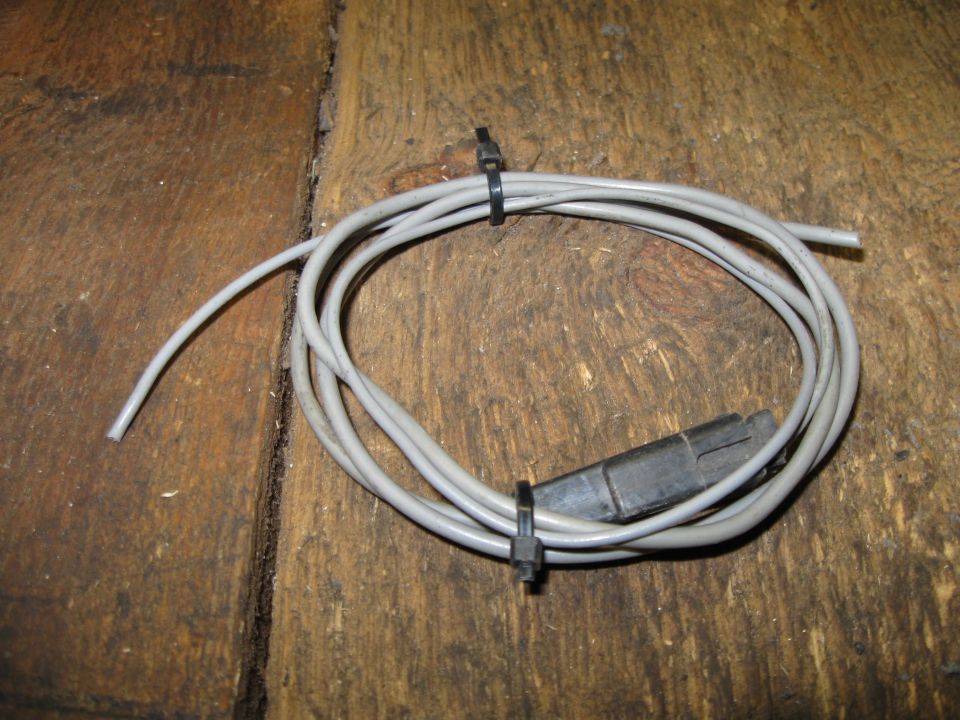 Gray wire harness with black connector, secured with zip ties on a wooden surface
