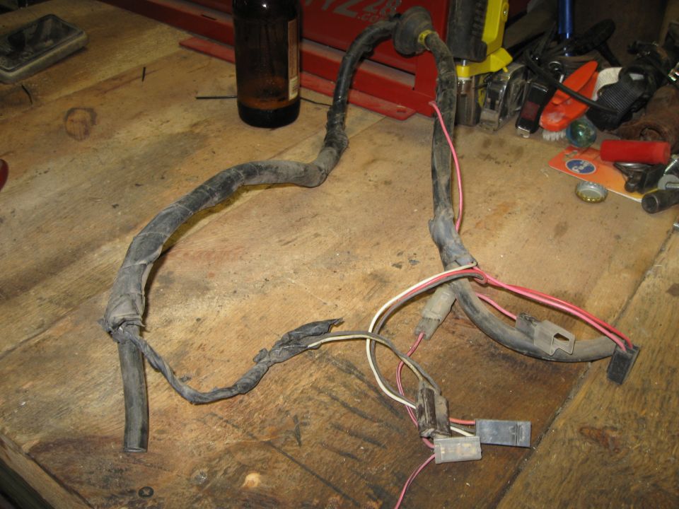 Engine wiring harness with black loom and red and white wires, lying on a wooden surface