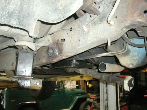 1985 Ford Bronco - A view of a vehicle's undercarriage, with a green Jeep partially visible in the background.