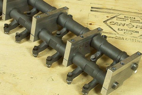 1972 Ford Ranchero - Multiple rocker arms are arranged on a wooden surface, with a crate bearing certification marks visible behind them.