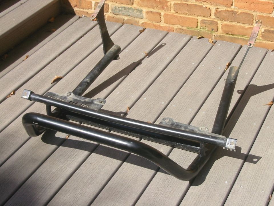 Black tubular metal bumper/brush guard with brackets on a wood deck