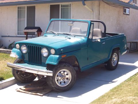 1970 Jeep Jeepster - A teal 1970 Jeep Jeepster is parked in front of a house, showing its front three-quarter view.